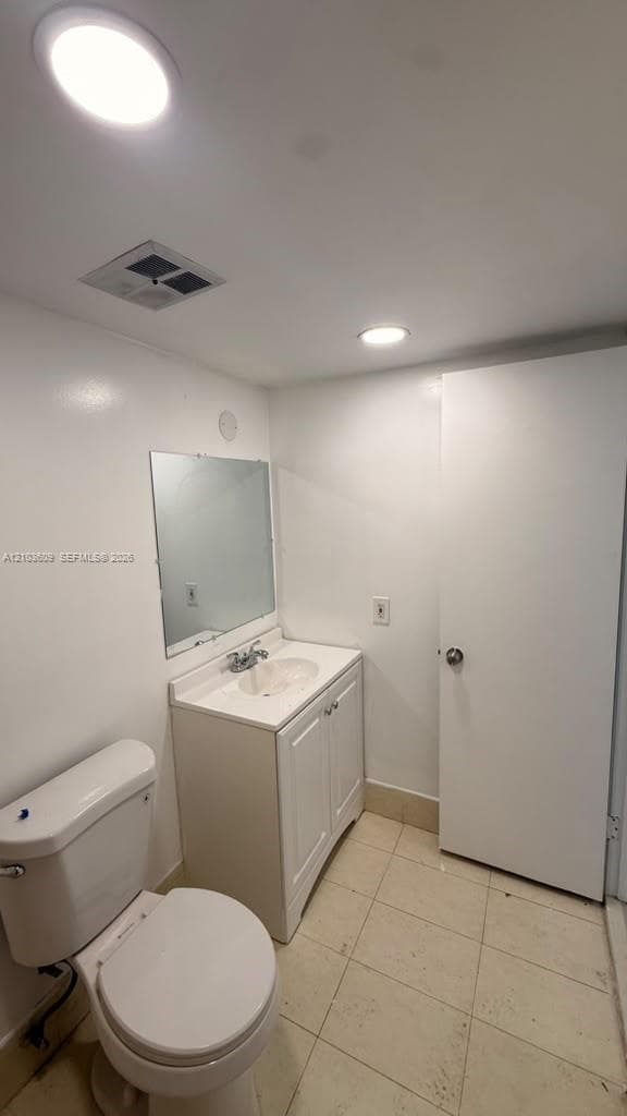 Bathroom featuring a white vanity cabinet with an integrated sink, polished chrome faucet, wall-mounted mirror, and tile flooring