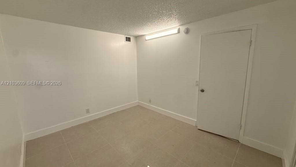 Neutral-toned tile flooring, solid-surface interior door, and linear wall-mounted lighting