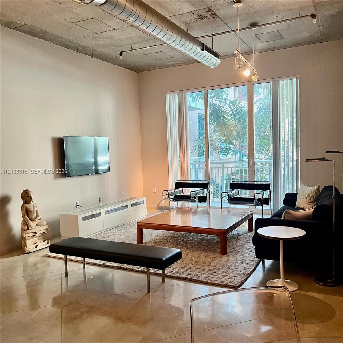 Industrial-style living space featuring polished concrete flooring, exposed concrete ceiling, exposed metallic ductwork, and floor-to-ceiling glass sliding doors
