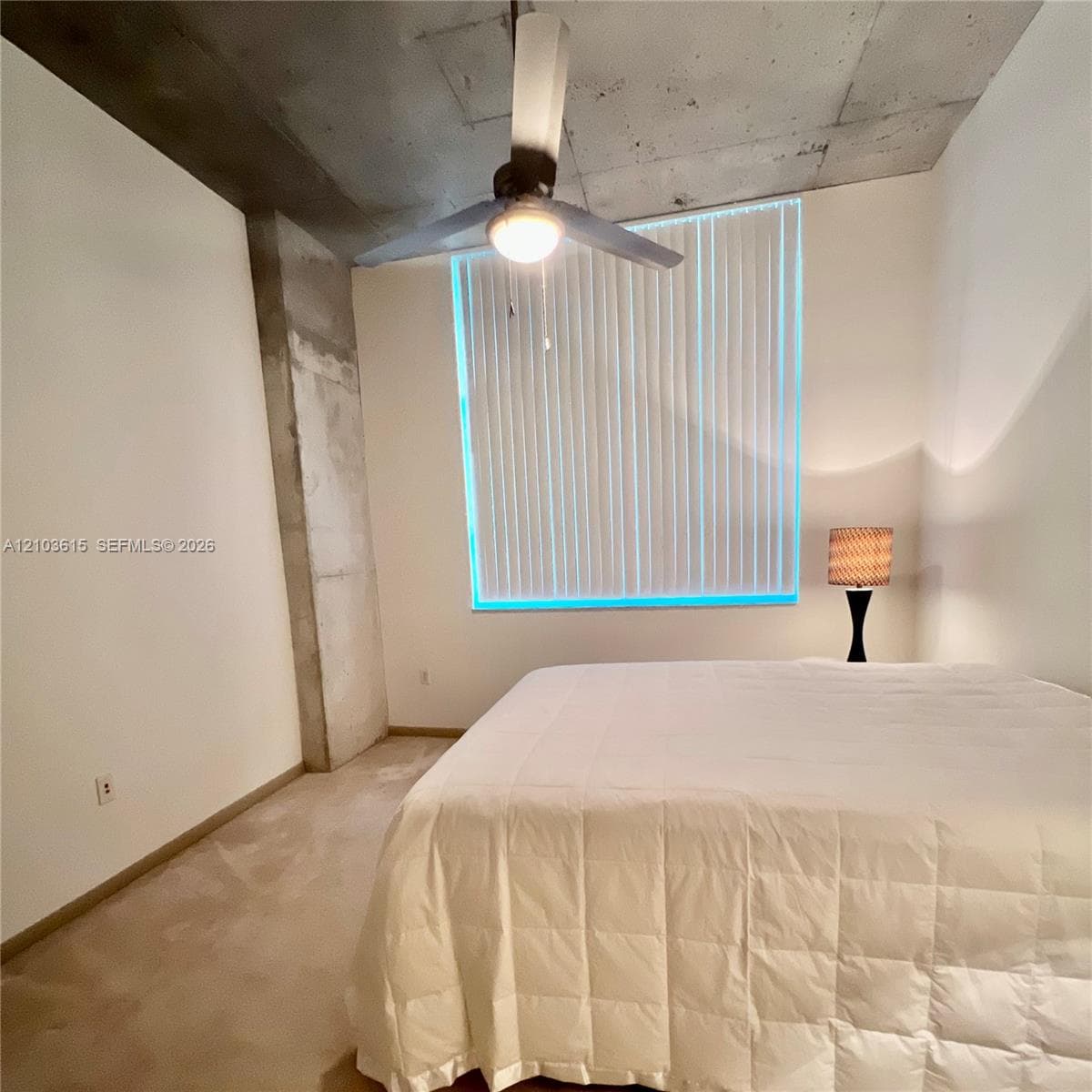Exposed concrete ceiling and structural pillar, ceiling-mounted fan with light fixture, and vertical window blinds