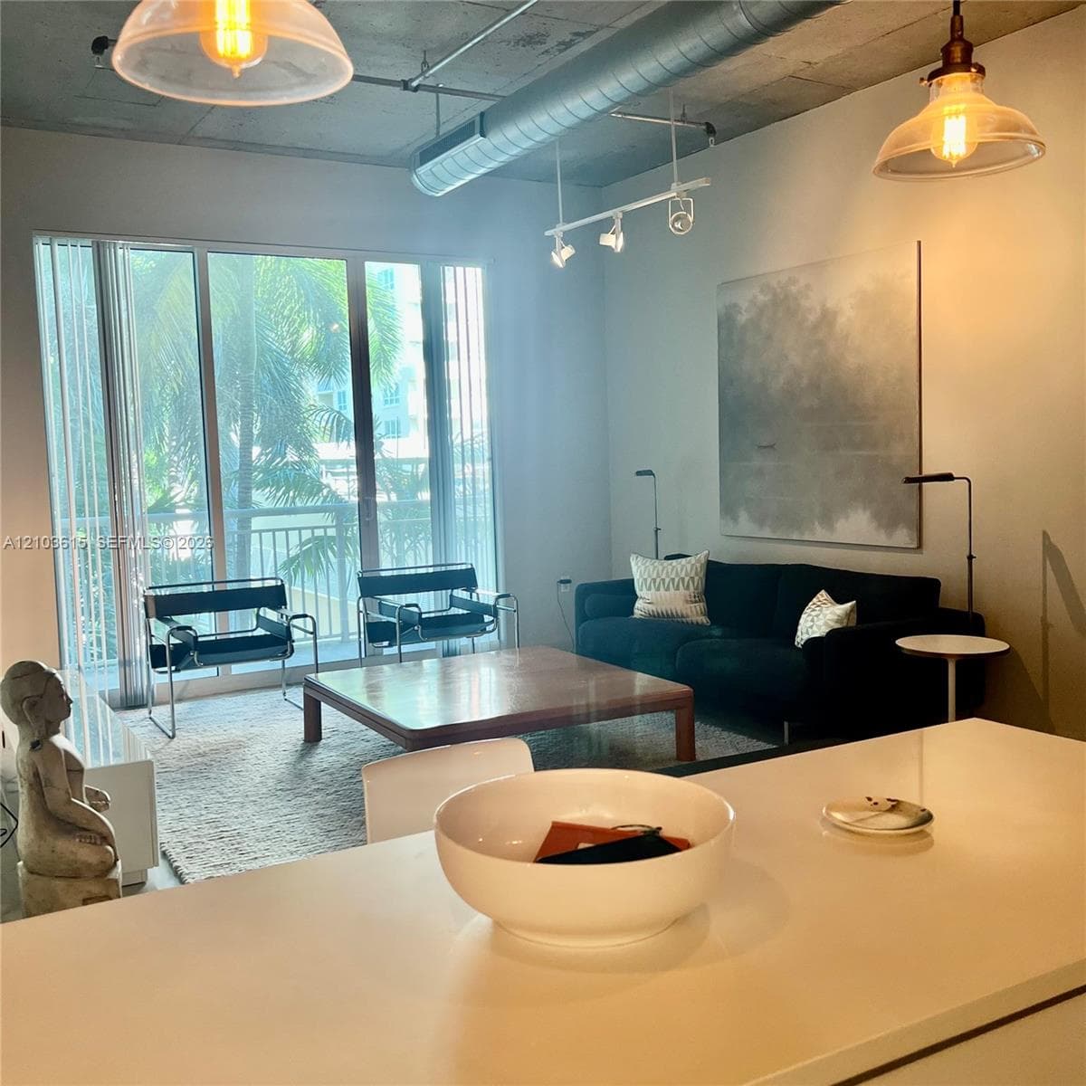 Industrial-style living space featuring an exposed concrete ceiling, exposed ductwork, floor-to-ceiling windows, track lighting, and pendant fixtures