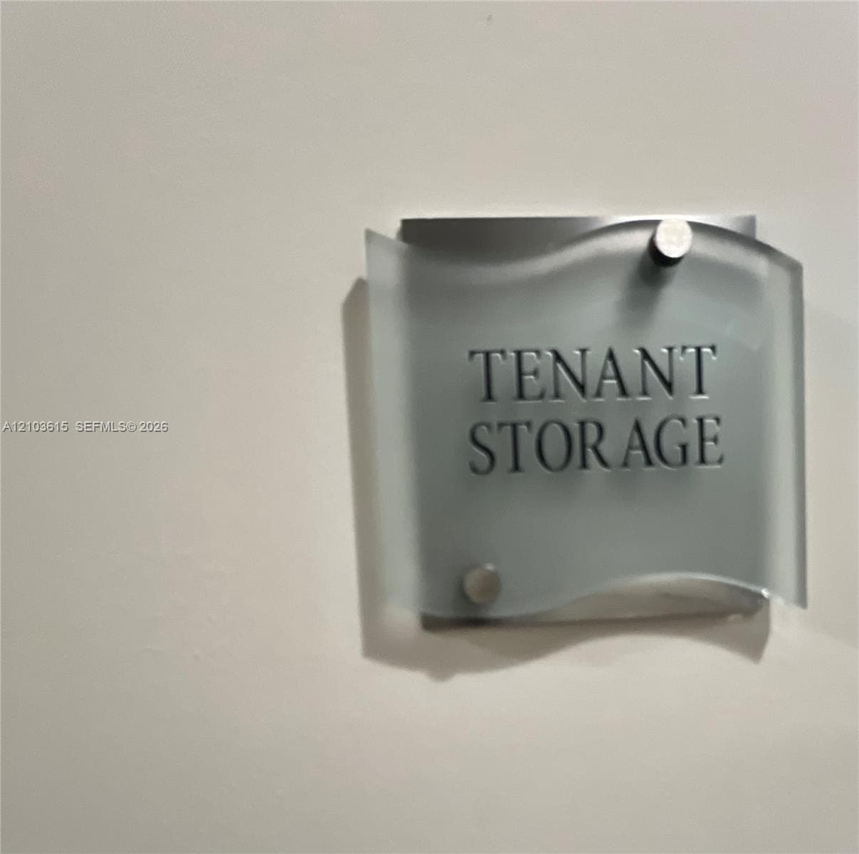 Wall-mounted signage featuring a brushed metal backplate, a frosted glass overlay with a wave-patterned edge, and secure silver-toned mounting hardware