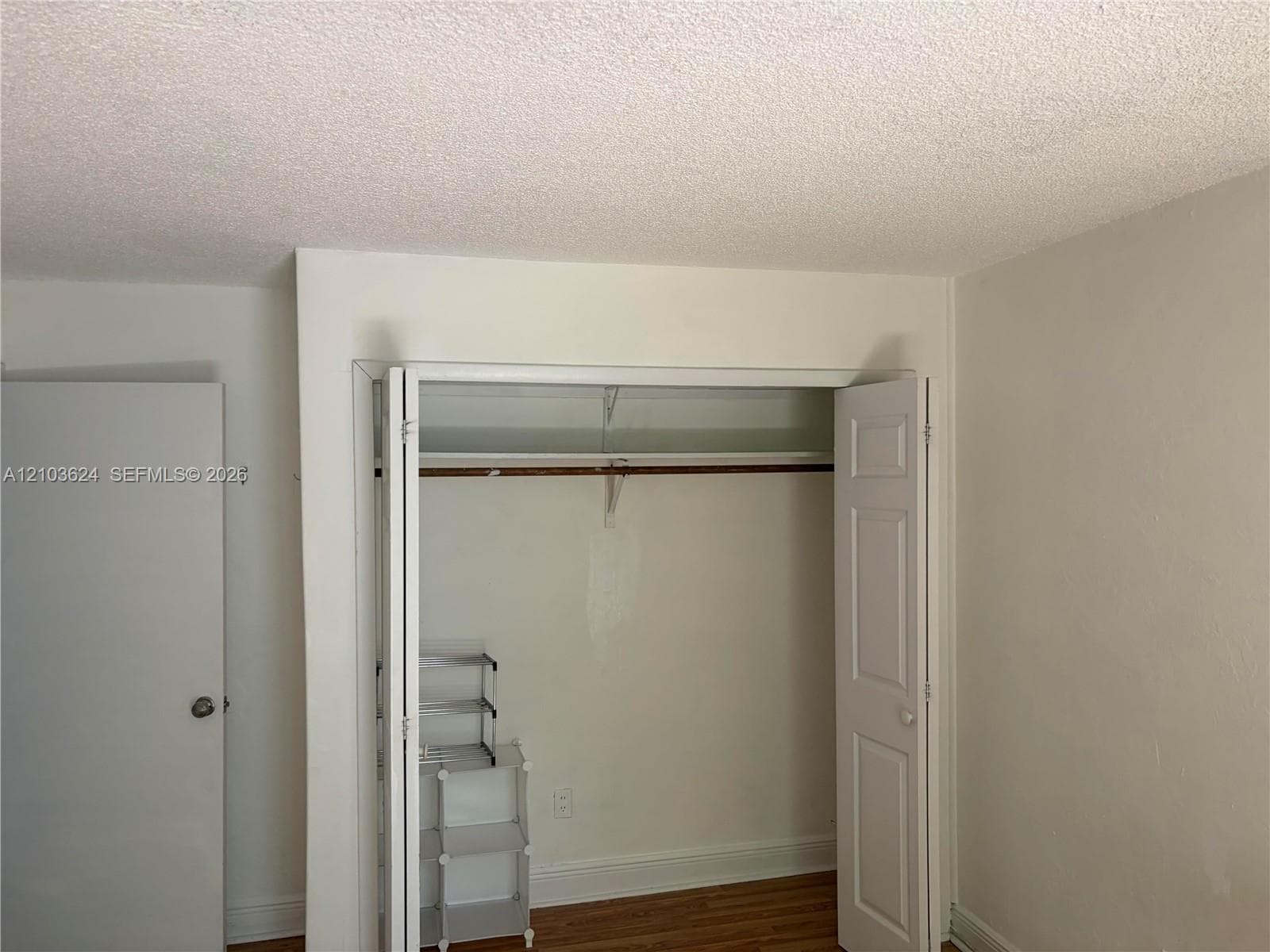 Bi-fold closet doors, wood-finish flooring, and a single-panel interior door