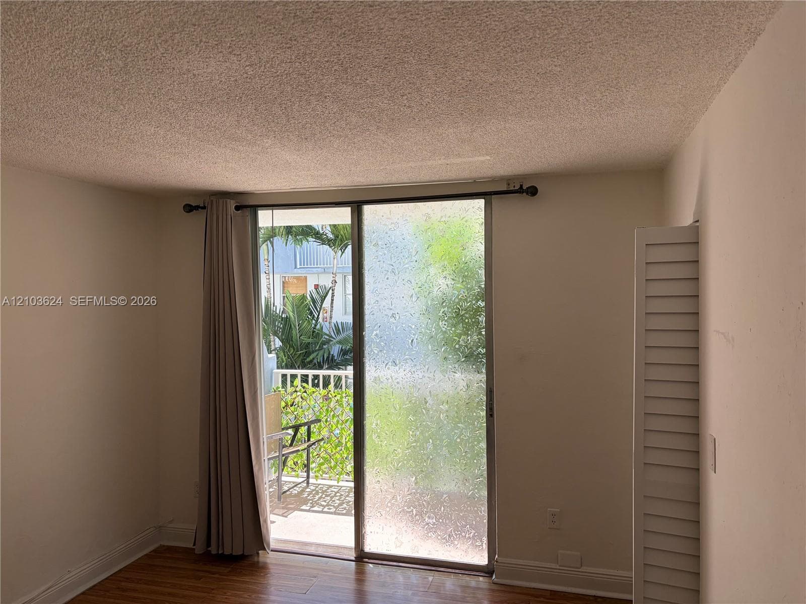 Sliding glass door with textured privacy glazing, wood-finish flooring, and white louvered bifold closet doors