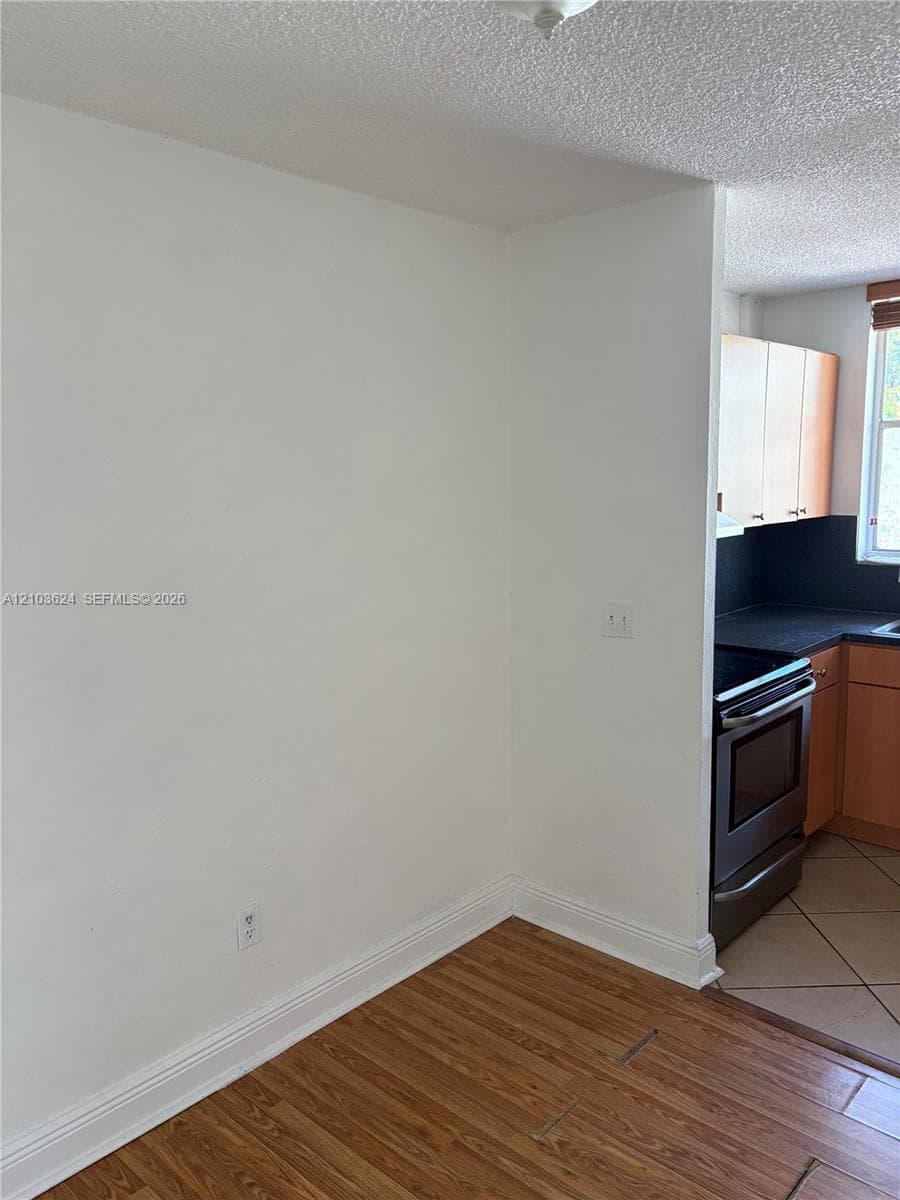 Kitchen featuring wood-finish cabinetry, stainless steel oven, dark countertops, and tile flooring