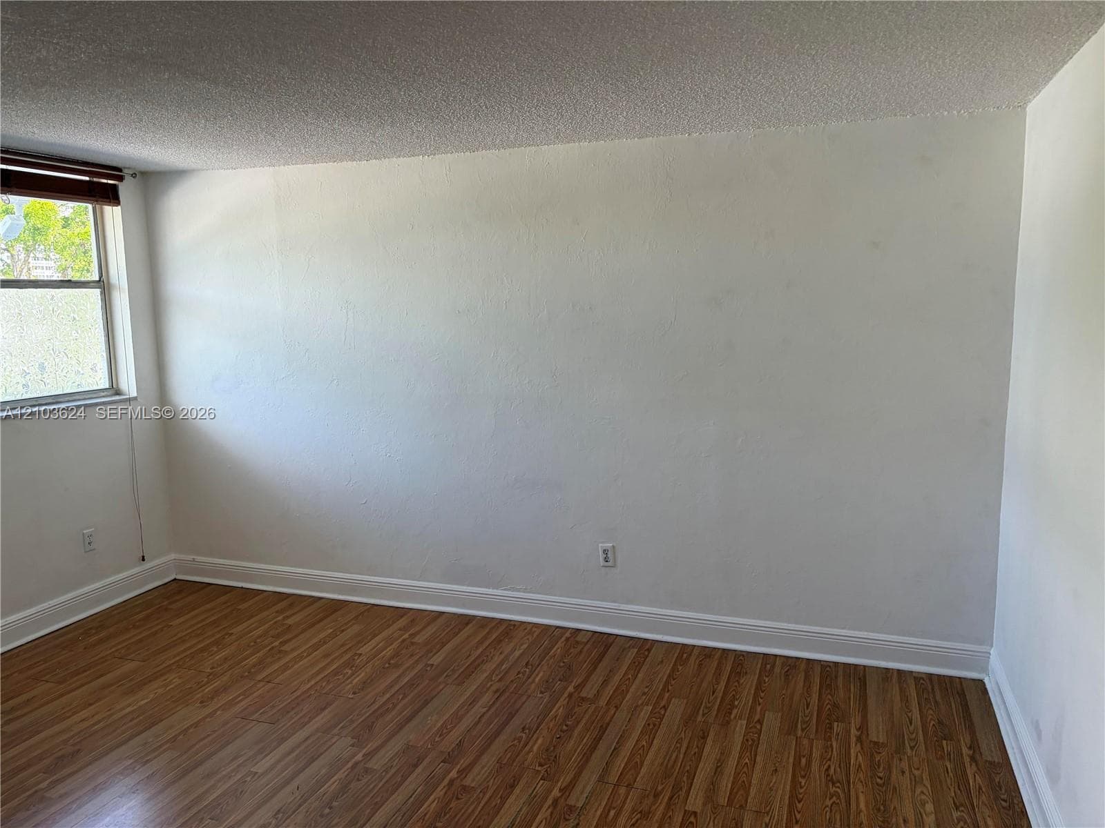 Room featuring wood-finish flooring, a single window, and textured ceiling