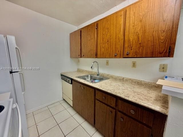 Kitchen featuring wood-finish cabinetry, a stainless steel sink, a dishwasher, and a refrigerator