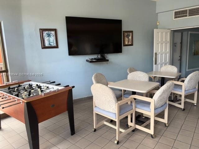 Wall-mounted television with shelving, light blue wall paint, and tile flooring