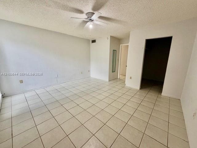 Spacious interior with tile flooring, white walls, and a ceiling fan with integrated lighting