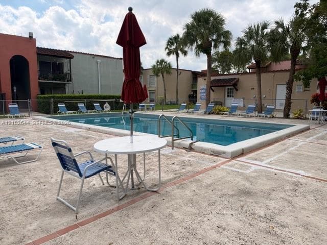 Rectangular swimming pool featuring a concrete deck and metal pool ladder