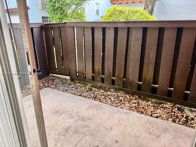 Private patio area with concrete flooring, framed by a wood-slat fence
