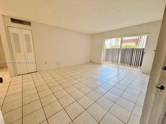 Light-colored tile flooring, white walls, louvered bi-fold doors, and a sliding glass door with vertical blinds