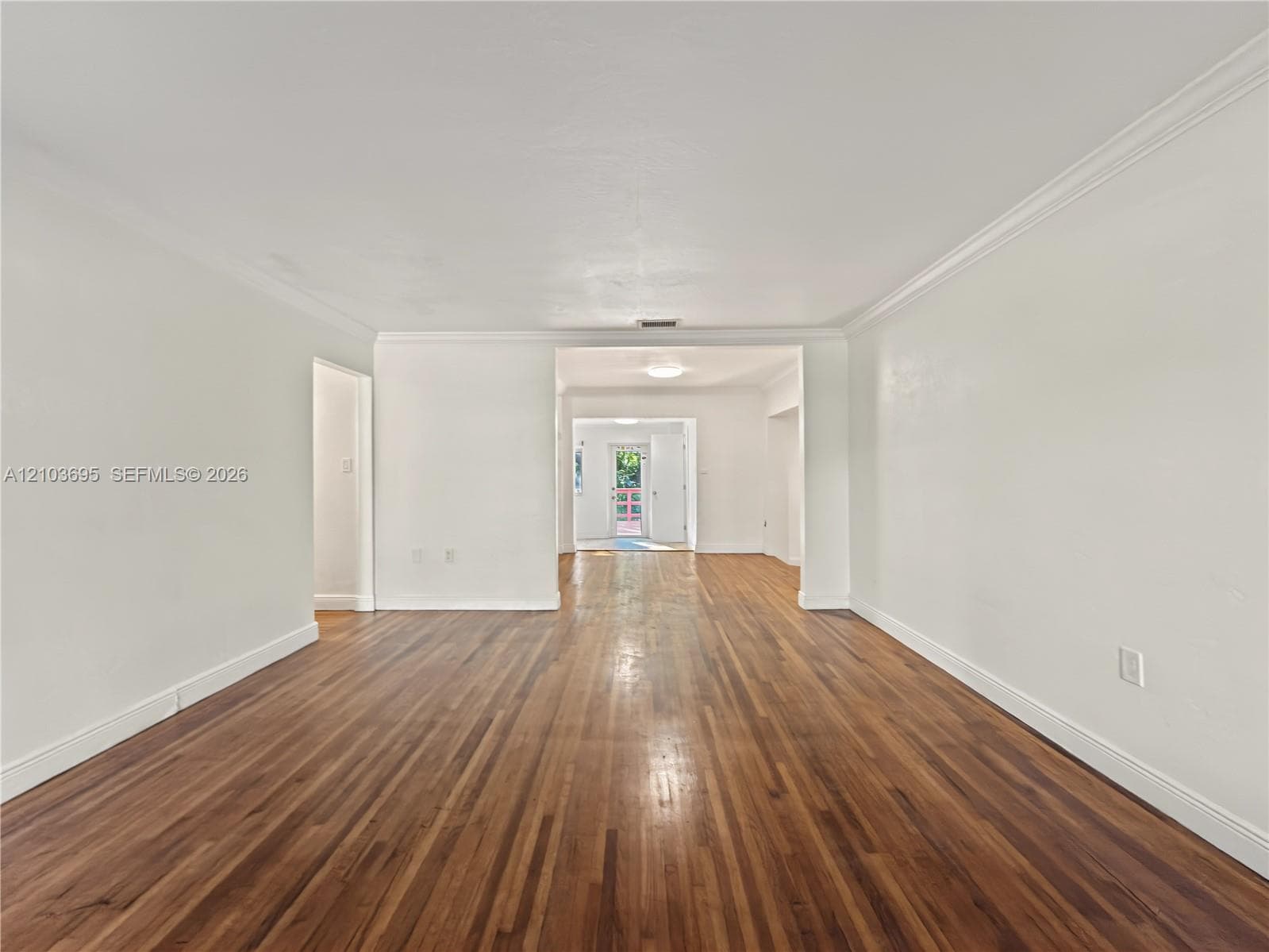 Interior space featuring wood-finish flooring, crown molding, and neutral wall paint