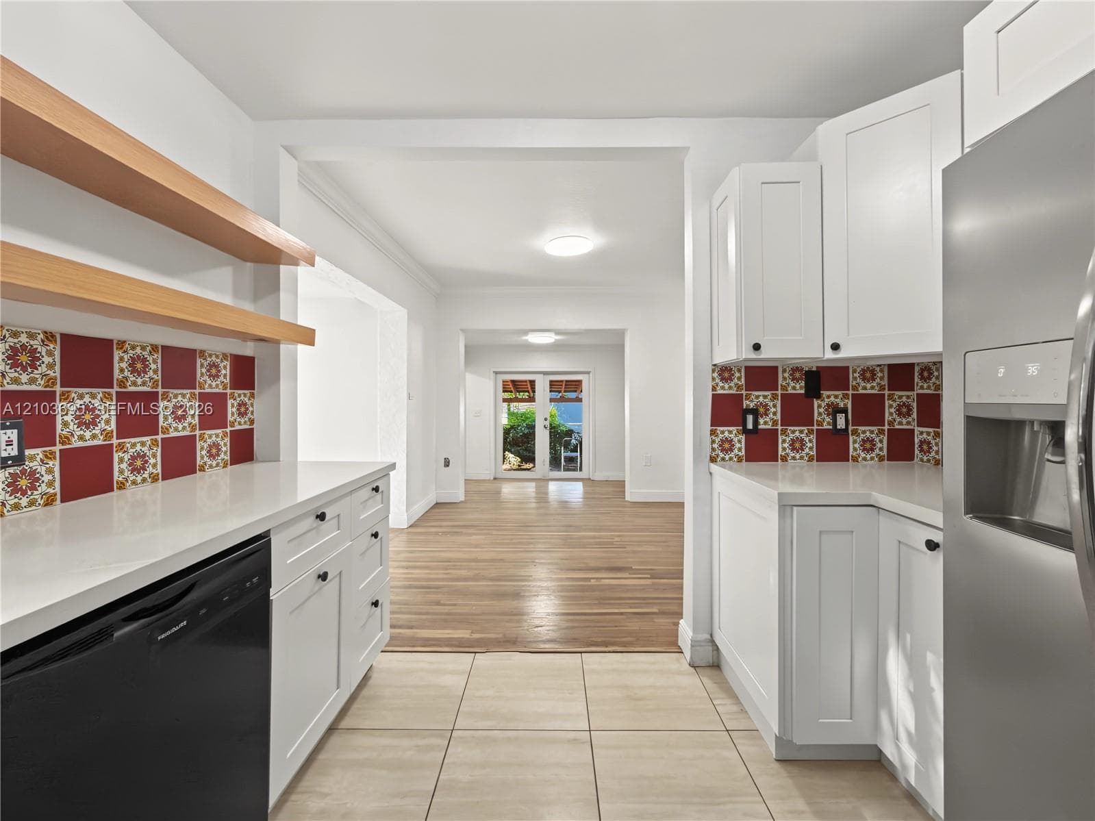 Kitchen featuring white shaker cabinetry, quartz countertops, decorative patterned tile backsplash, natural wood-finish open shelving, and tile flooring