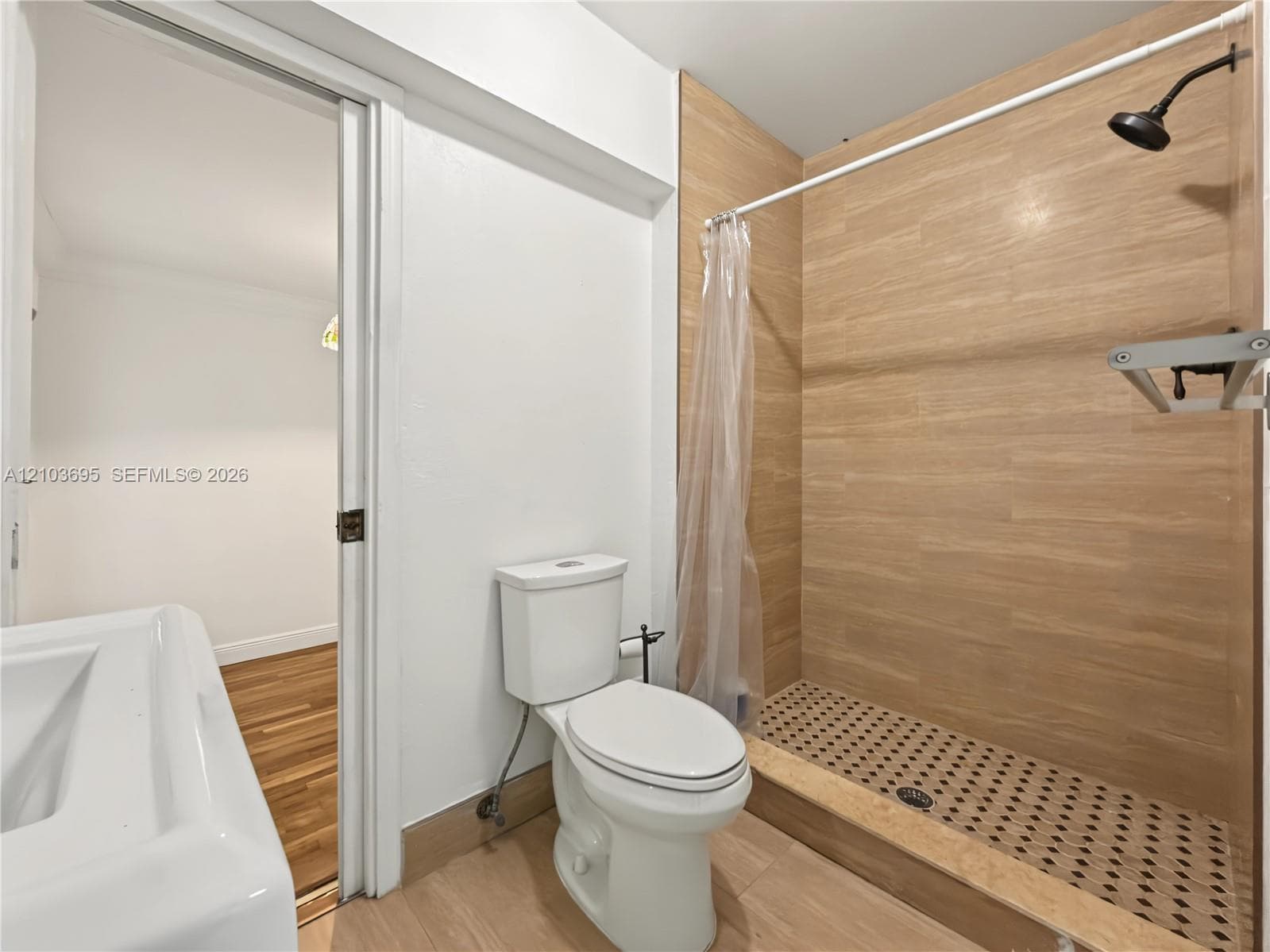 Bathroom featuring a walk-in shower with wood-finish tile surround, geometric patterned tile flooring, and a wall-mounted shower head