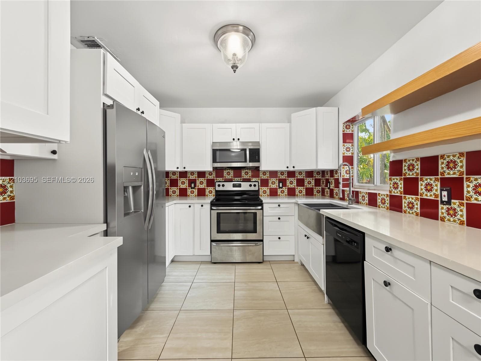 Kitchen featuring white cabinetry, solid-surface countertops, decorative tile backsplash, stainless steel appliances, and floating wooden shelving