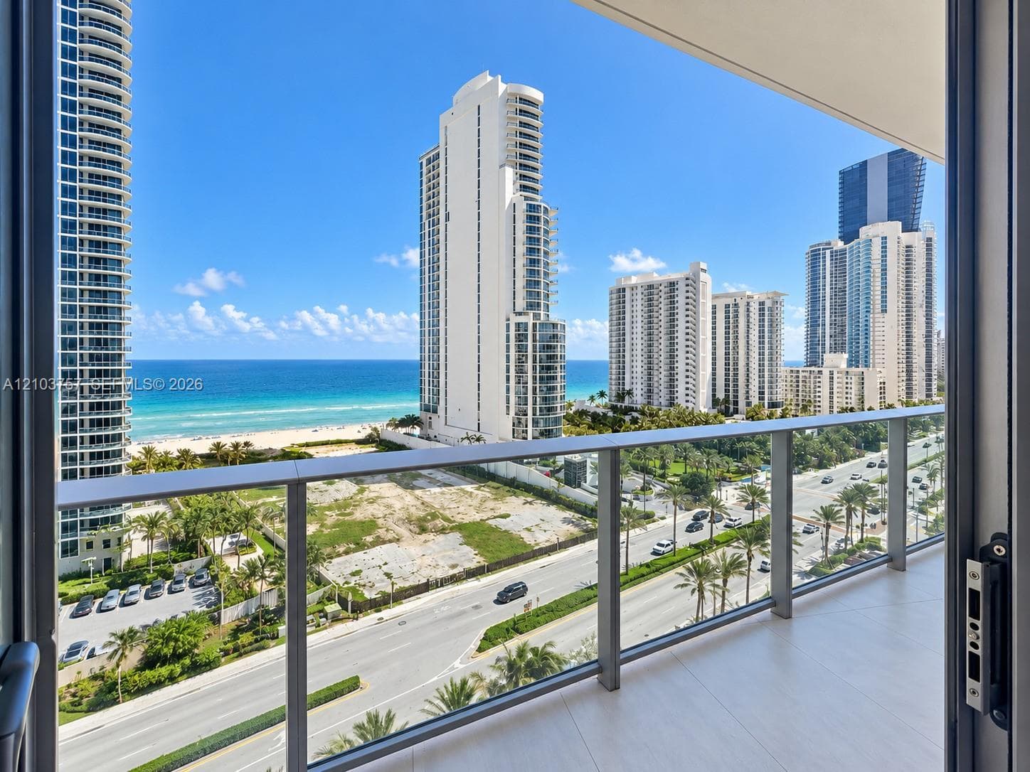 Balcony with glass panel railings, wood-finish flooring, and coastal scenery