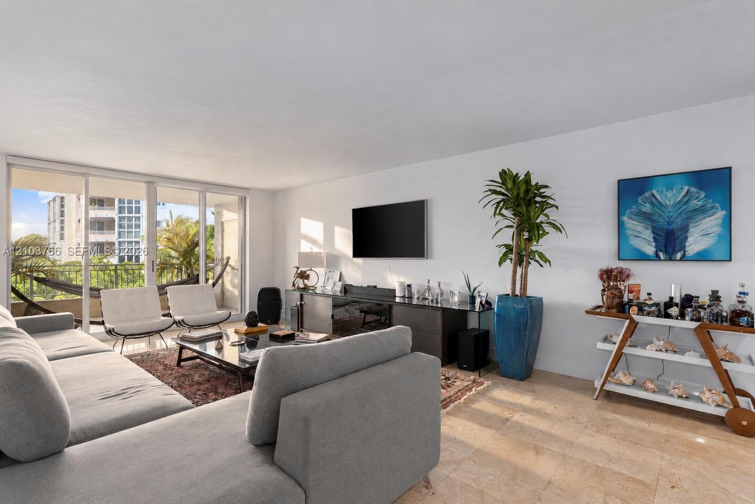 Living area featuring neutral stone flooring, floor-to-ceiling glass sliding doors, and access to a balcony with metal railings