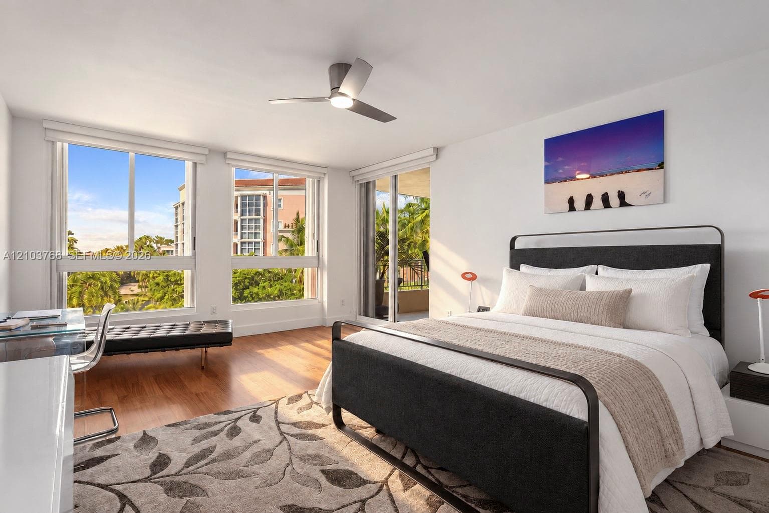 Room featuring wood-finish flooring, large windows, a ceiling fan, and access to a private balcony