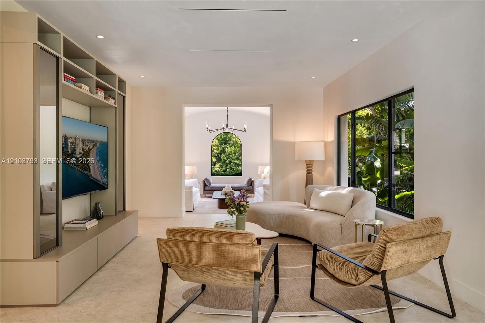 Vaulted ceiling featuring a central matte black chandelier, arched window, and dual rectangular windows with black frames