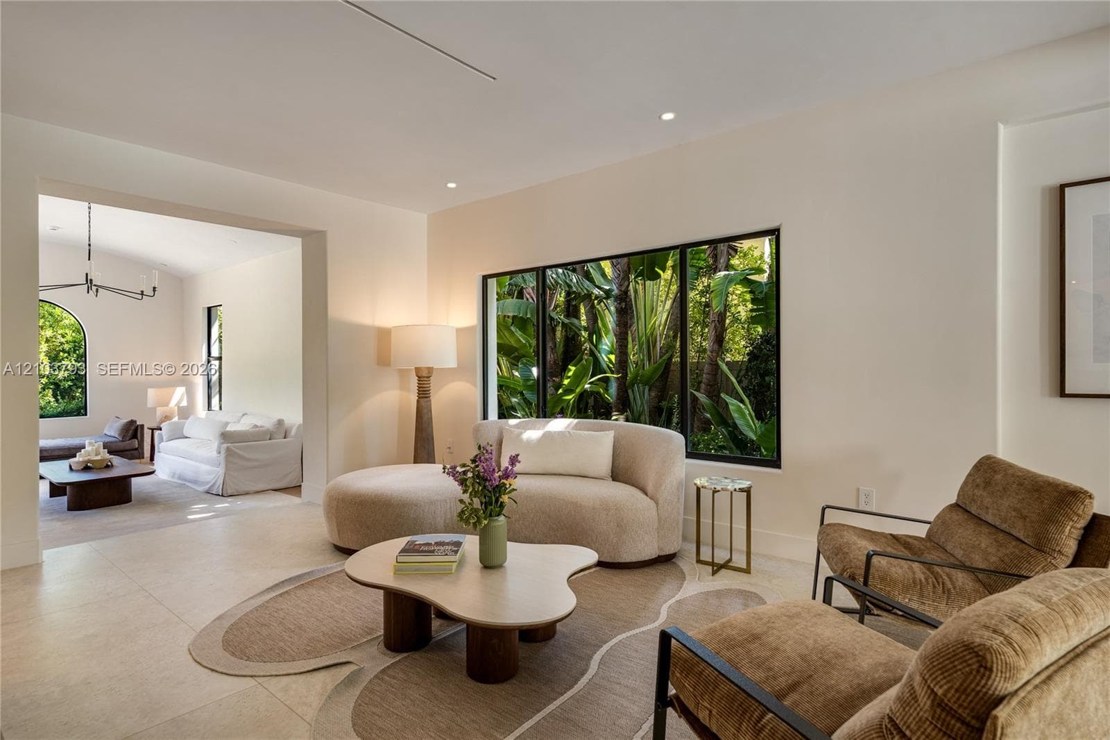 Large-format windows with black frames, recessed ceiling lighting, and neutral stone-finish flooring