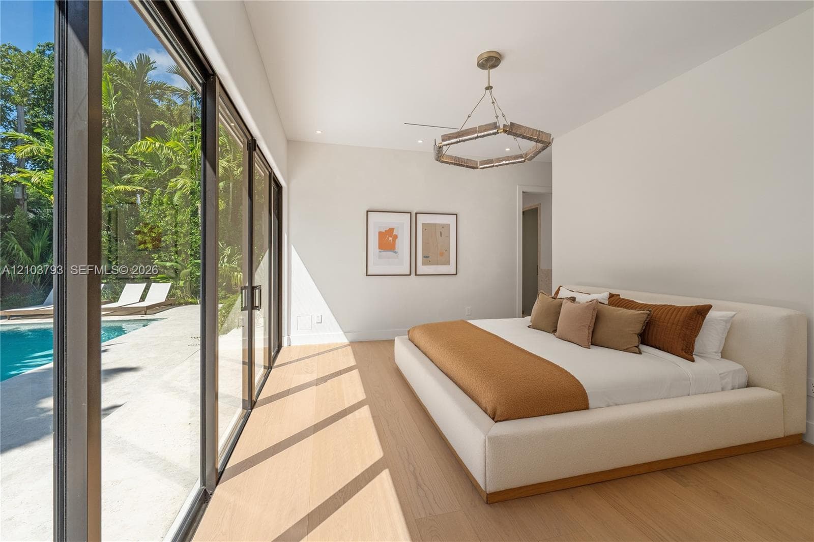 Floor-to-ceiling sliding glass walls, wood-finish flooring, recessed lighting, and geometric metal chandelier