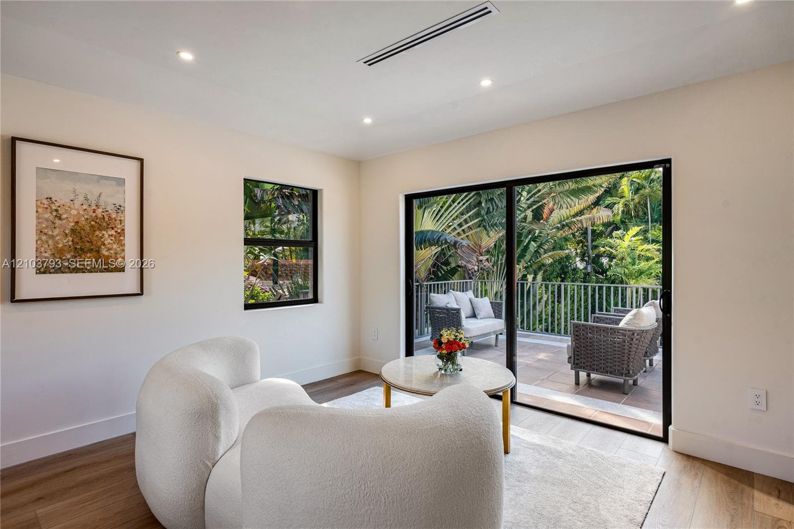 Recessed lighting, wood-finish flooring, sliding glass door, and a balcony with black metal railings