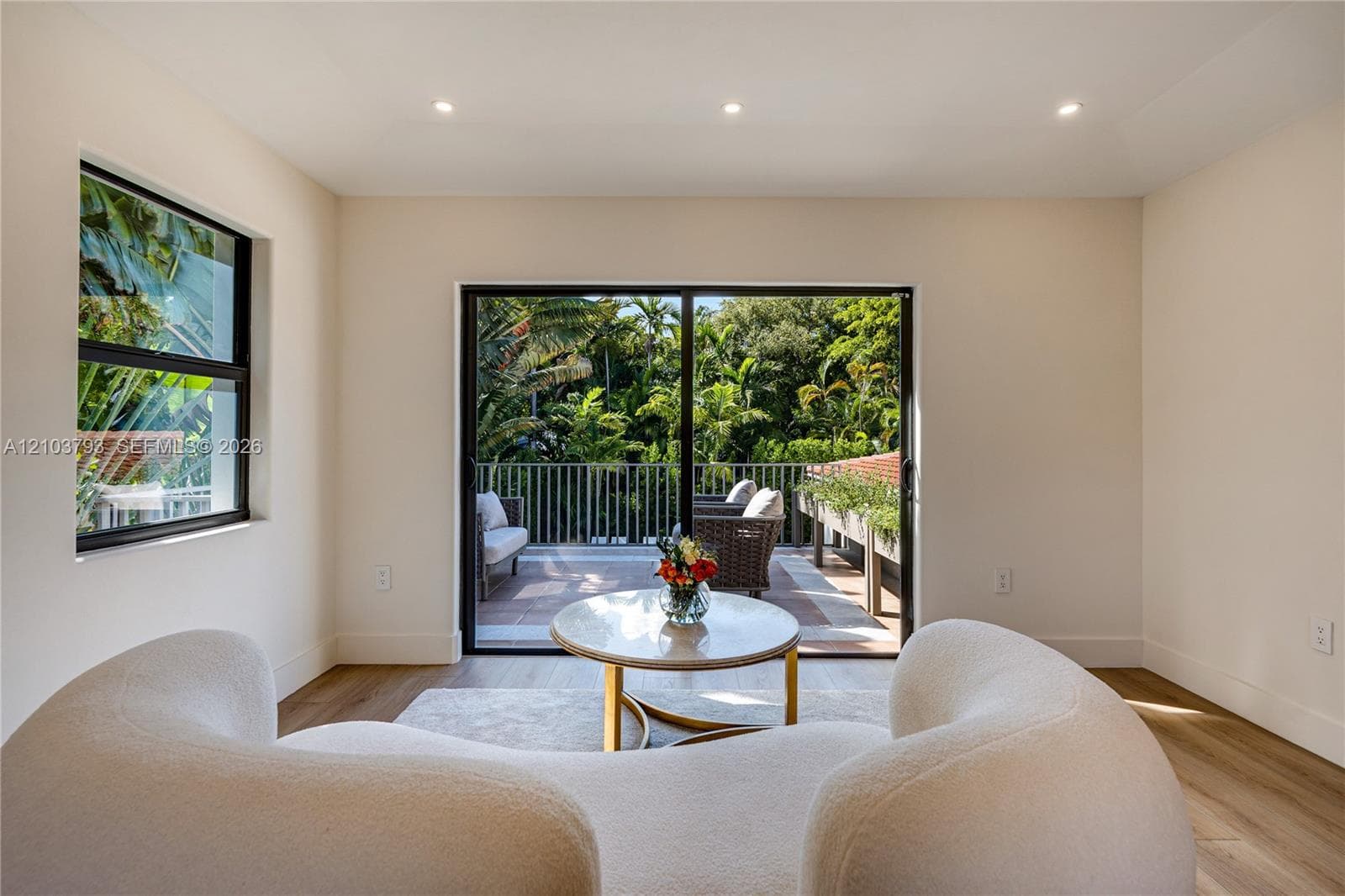 Large-format sliding glass doors with dark frames, paired with an exterior balcony featuring metal railings and tile flooring