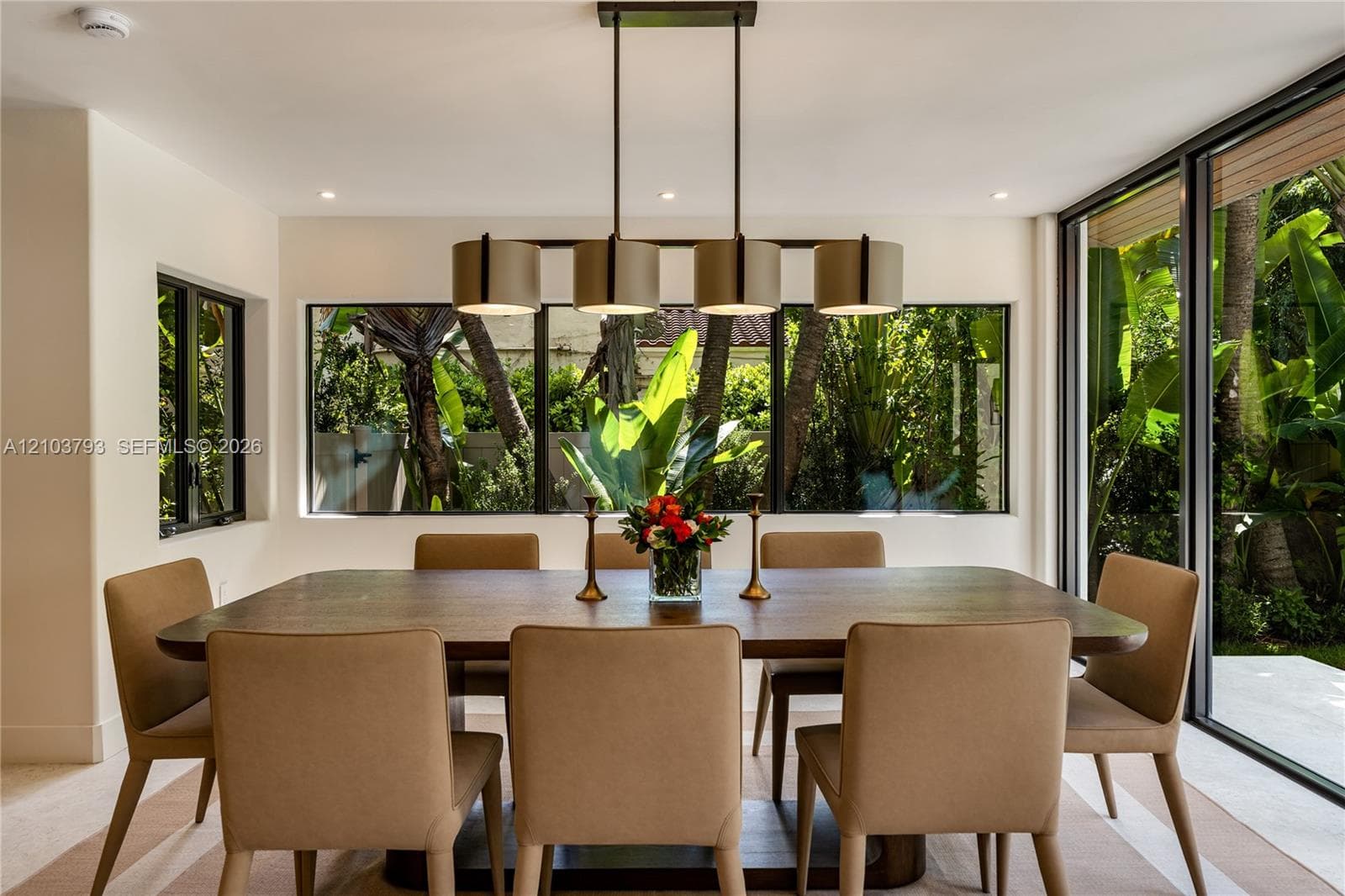 Multi-light linear pendant fixture with cylindrical shades, expansive ribbon windows, and floor-to-ceiling glass sliding doors