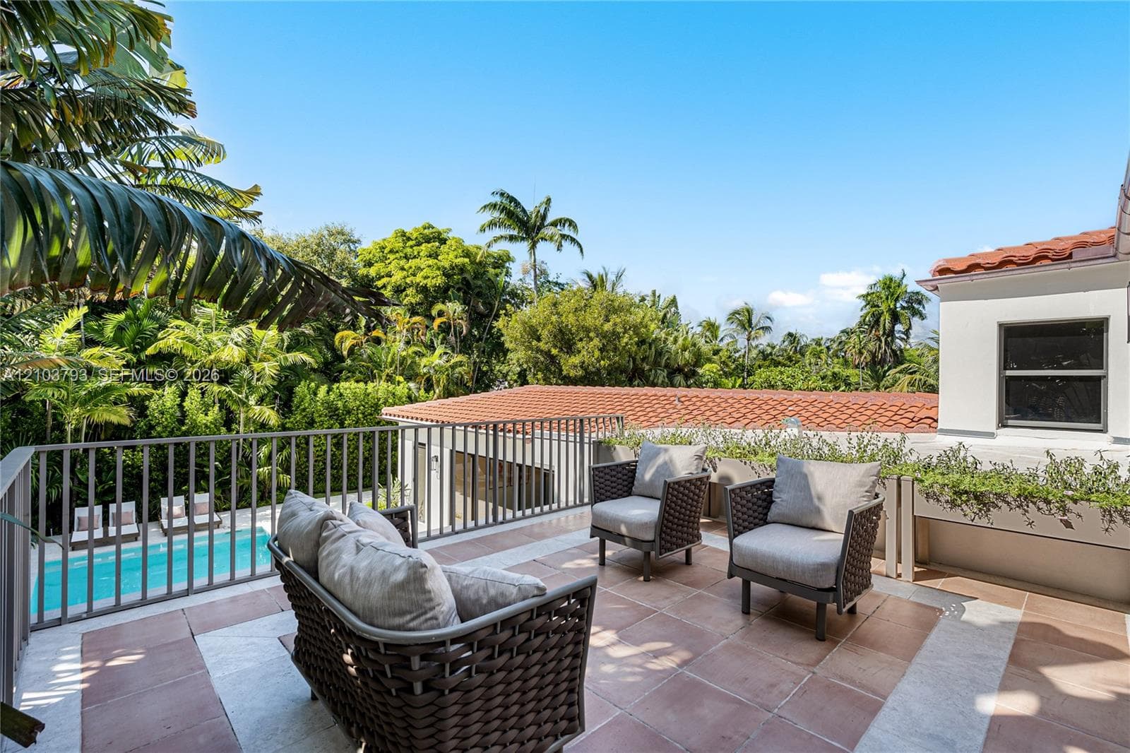 Outdoor space featuring a swimming pool with integrated spa, stone-finish decking, large-format sliding glass doors, and a terracotta tile roof