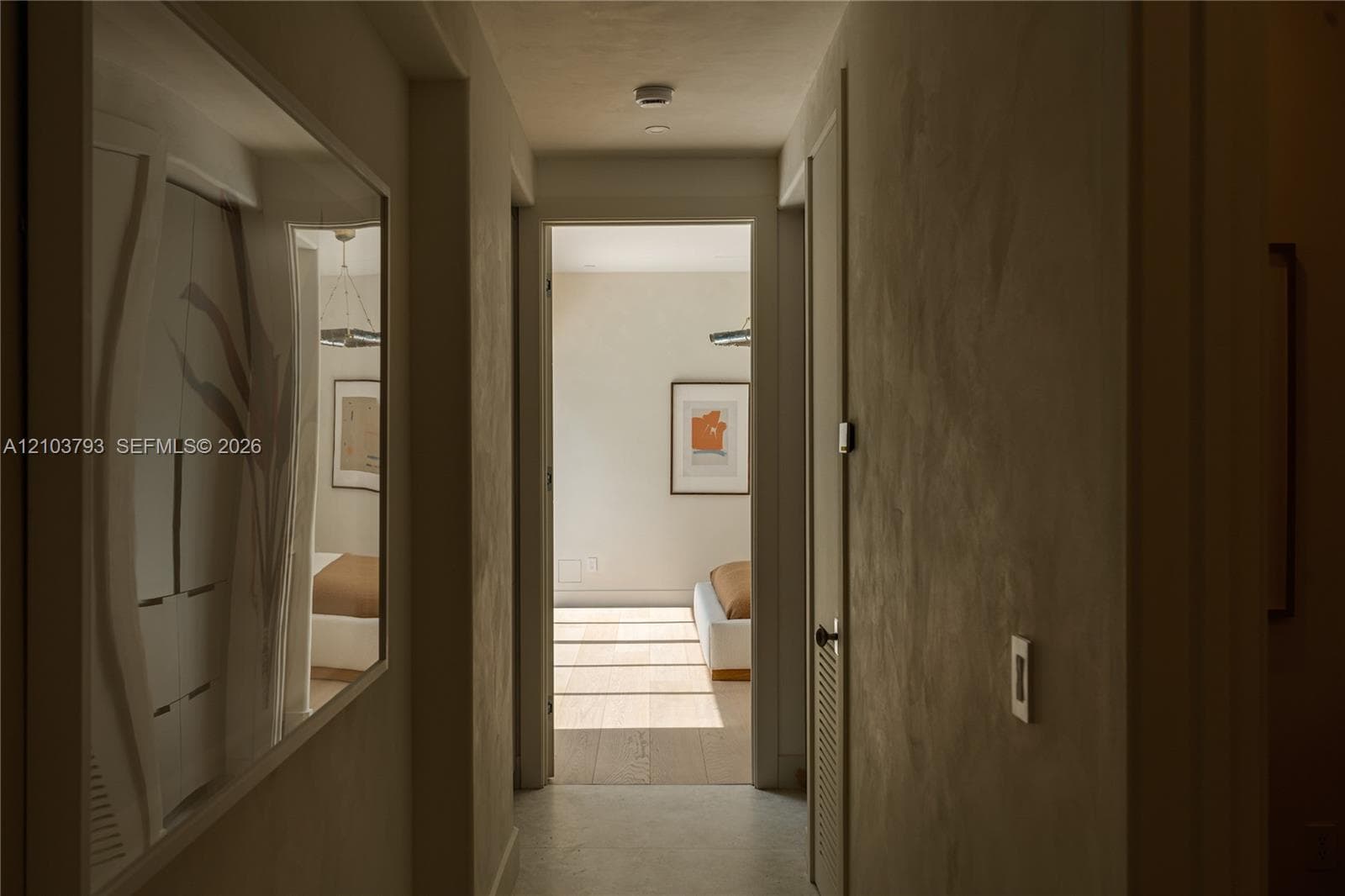 Floor-to-ceiling sliding glass doors, light-toned wood-finish flooring, and a contemporary geometric chandelier
