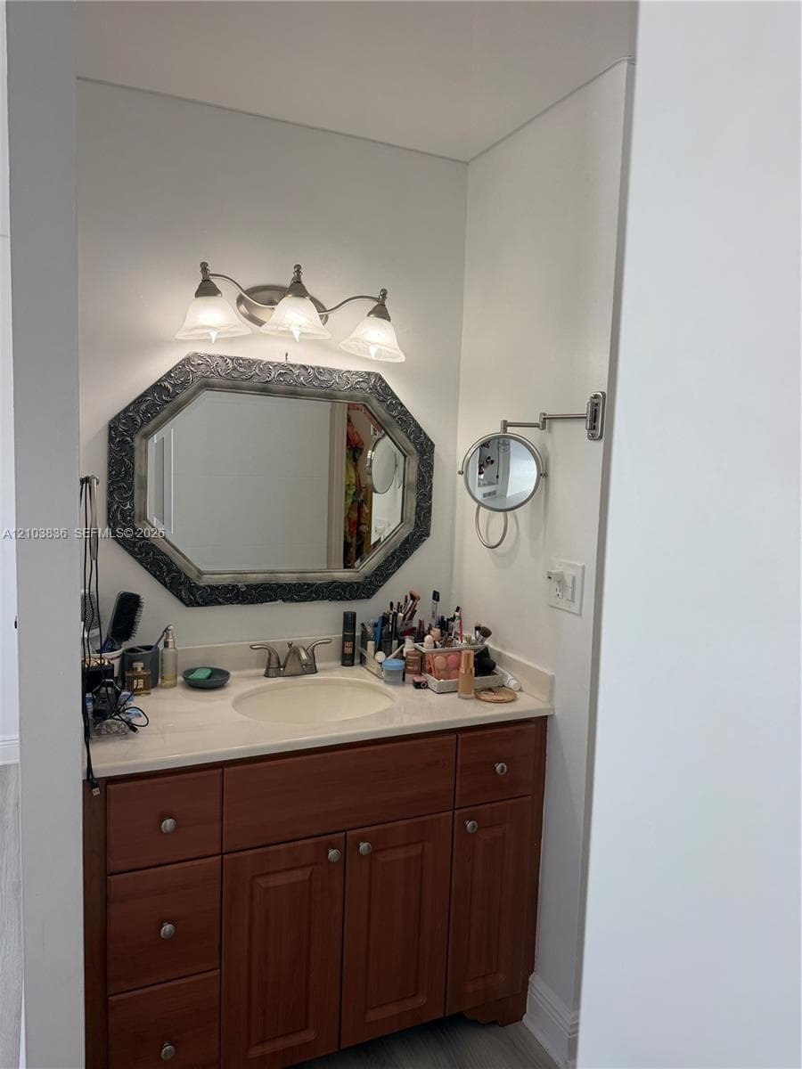 Vanity with an integrated sink, wood-finish cabinetry, and a light-toned countertop