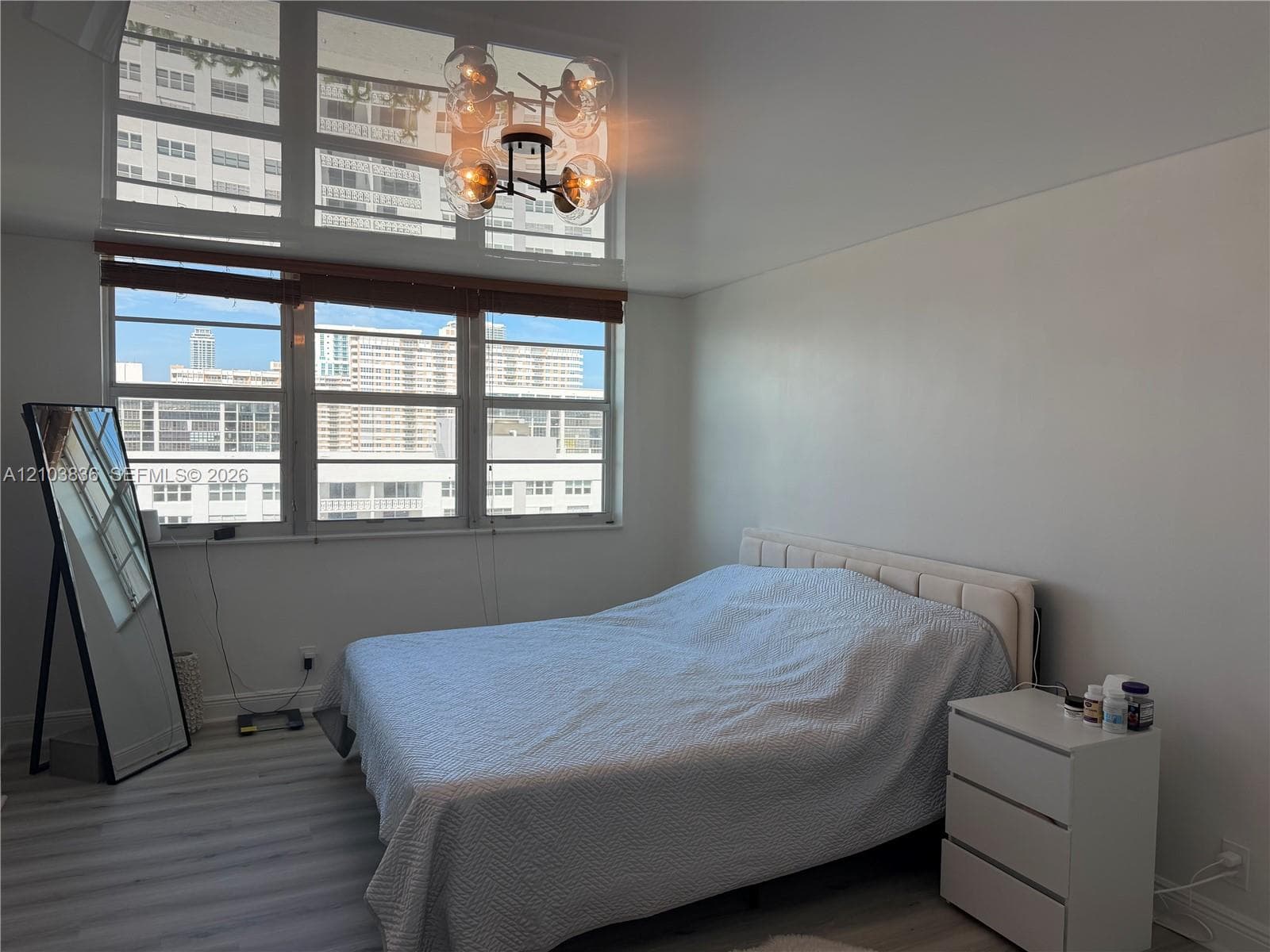 Expansive windows with high-level transom, contemporary chandelier with clear glass globes, and wood-finish flooring