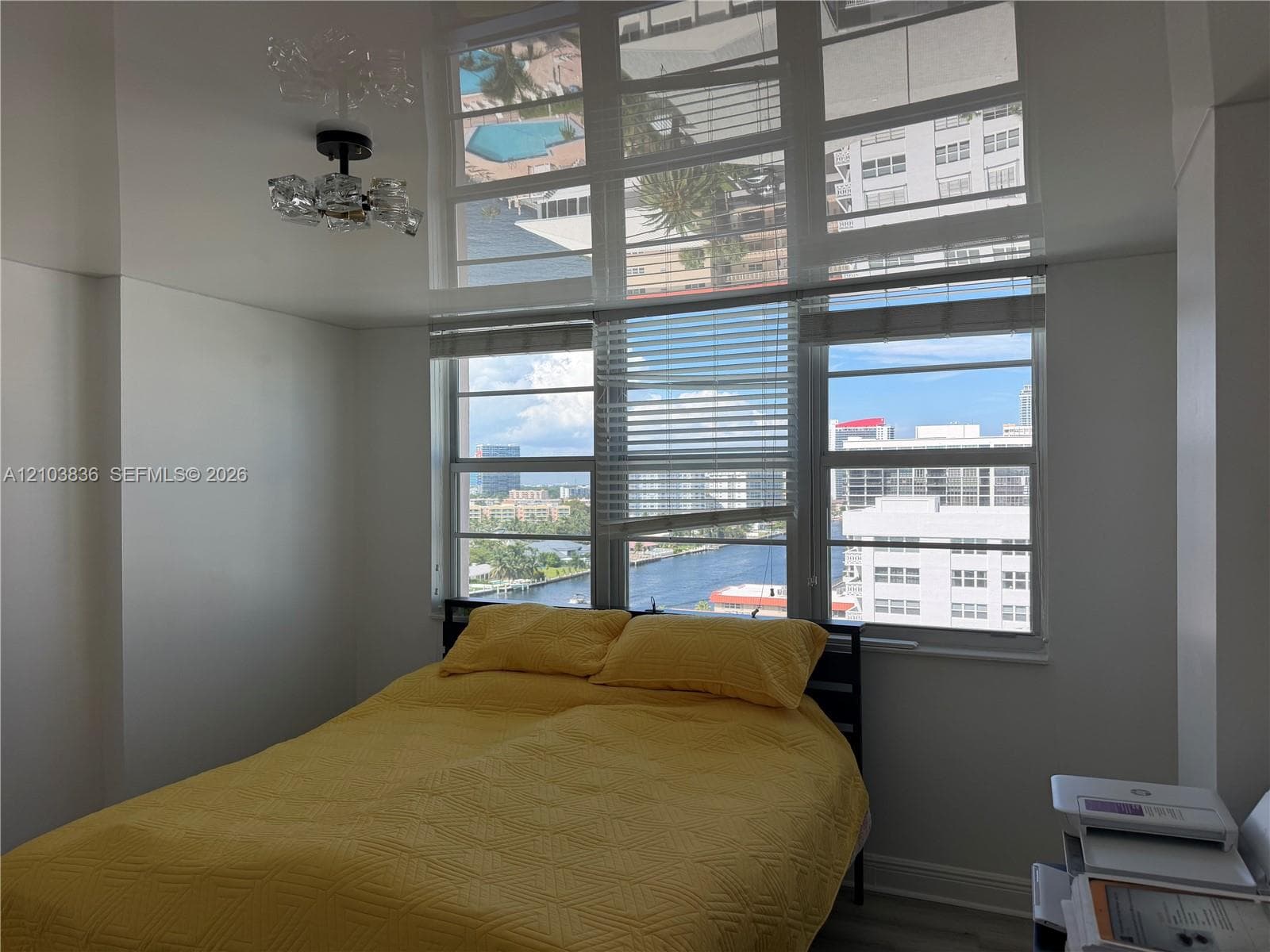 Floor-to-ceiling windows with horizontal blinds, showcasing city and water views