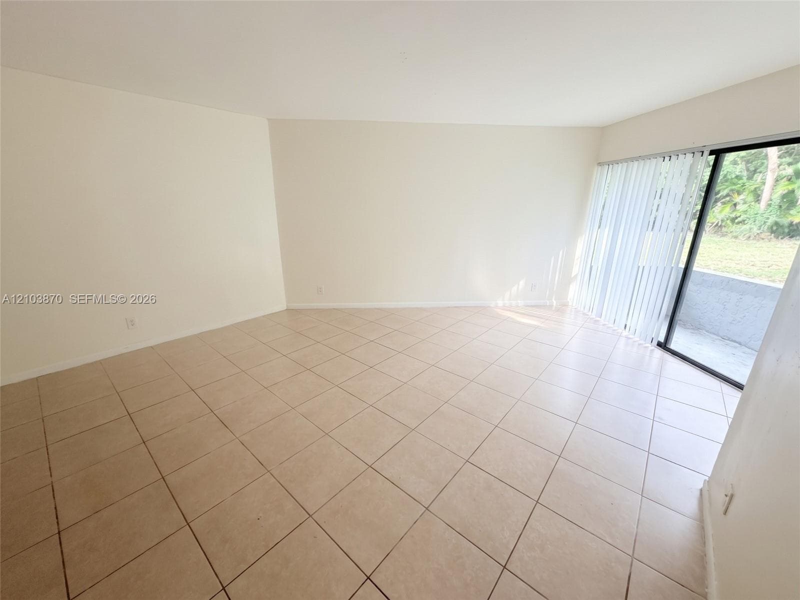 Neutral-toned ceramic tile flooring laid on a diagonal, crisp white walls, and a large sliding glass door featuring vertical blinds