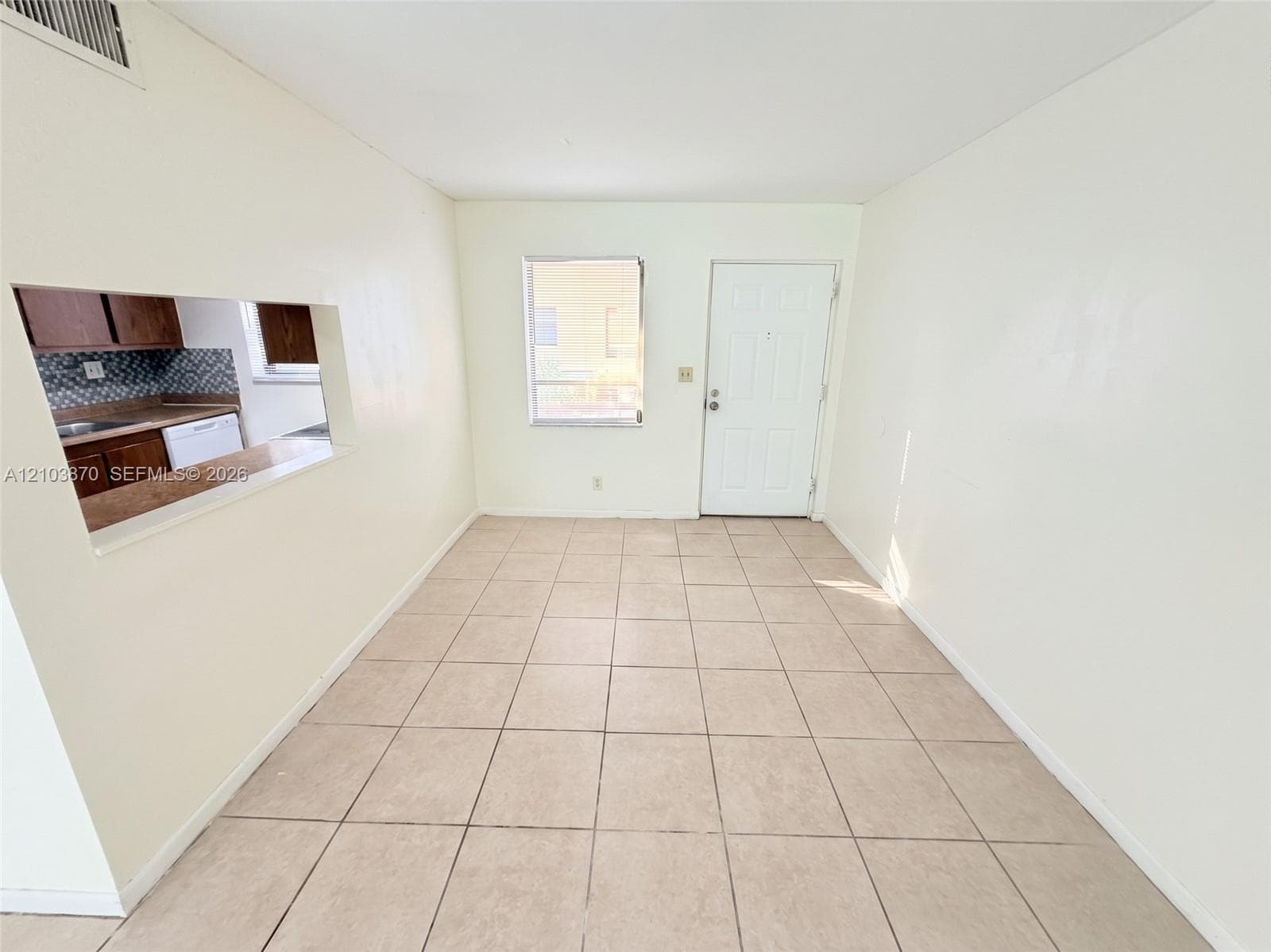 Neutral-toned ceramic tile flooring, interior pass-through opening to kitchen, and six-panel exterior door