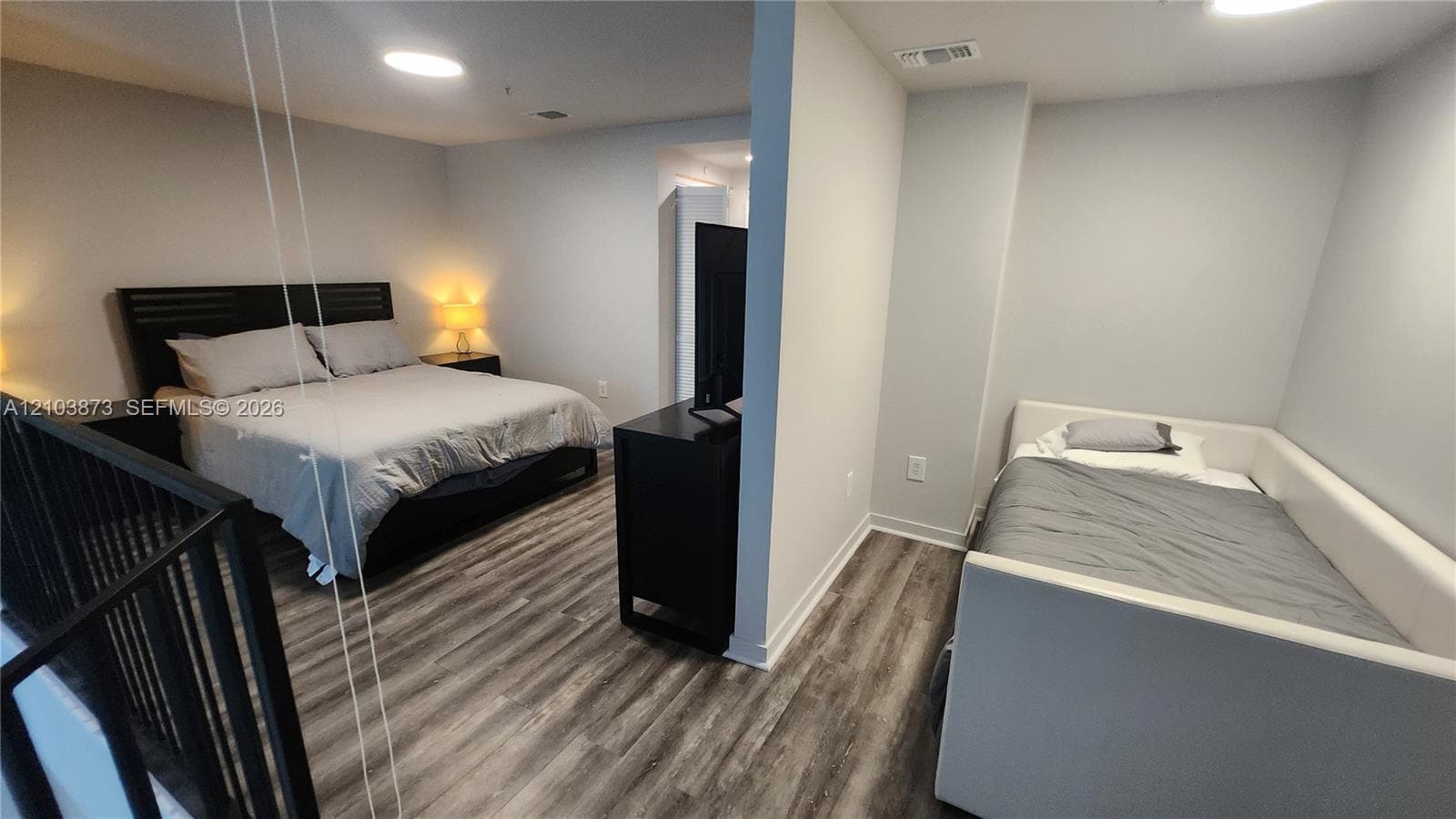 Wood-finish flooring, recessed ceiling lighting, and a black metal railing