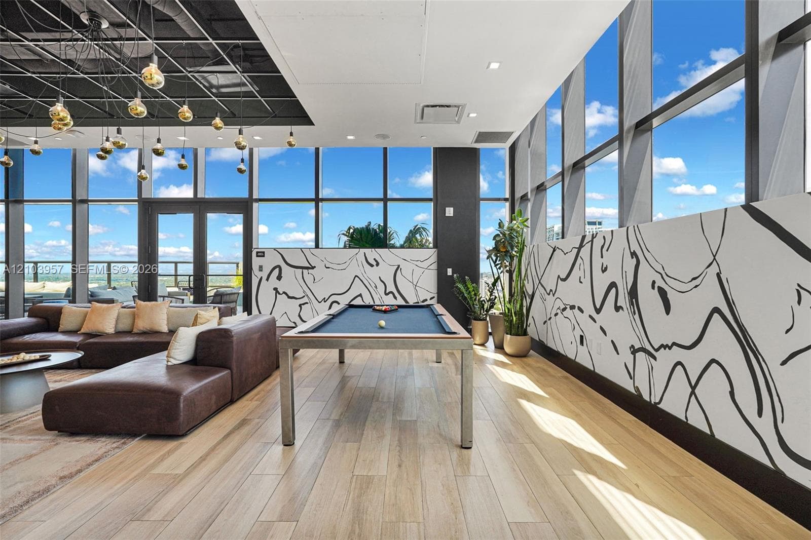 Floor-to-ceiling windows, wood-finish flooring, exposed ceiling, double-door outdoor access, and contemporary wall art