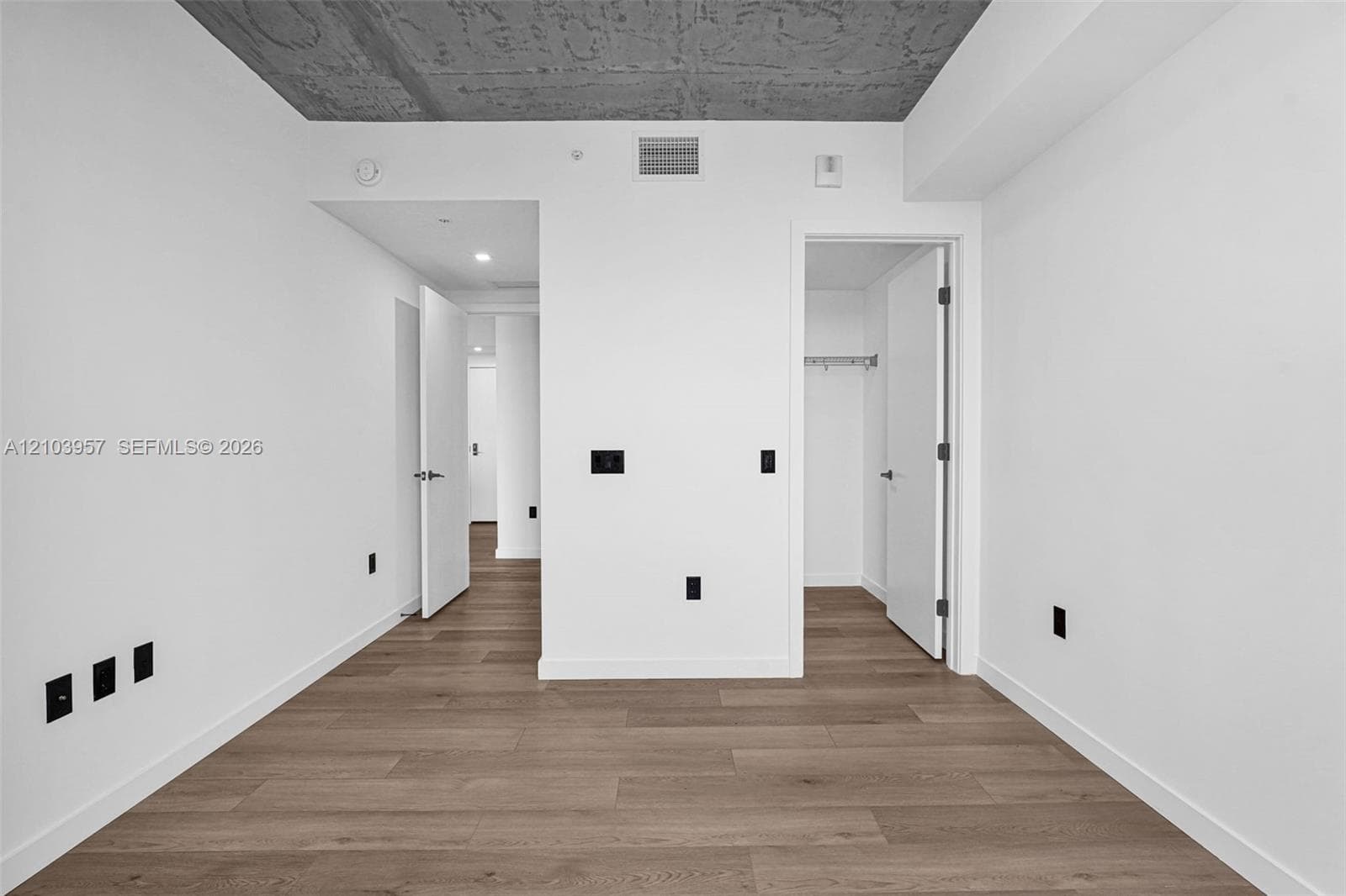 Wood-finish flooring with white baseboards and neutral white walls