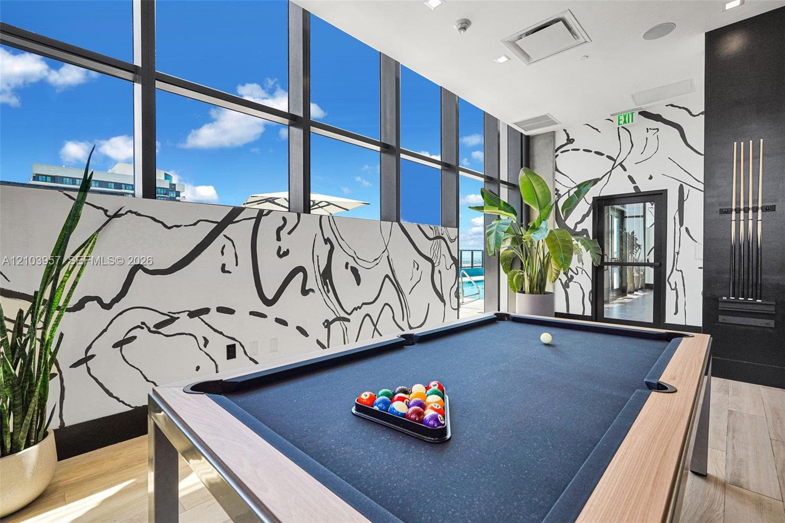 Expansive window wall, contemporary wall mural, wood-finish flooring, and a built-in cue rack