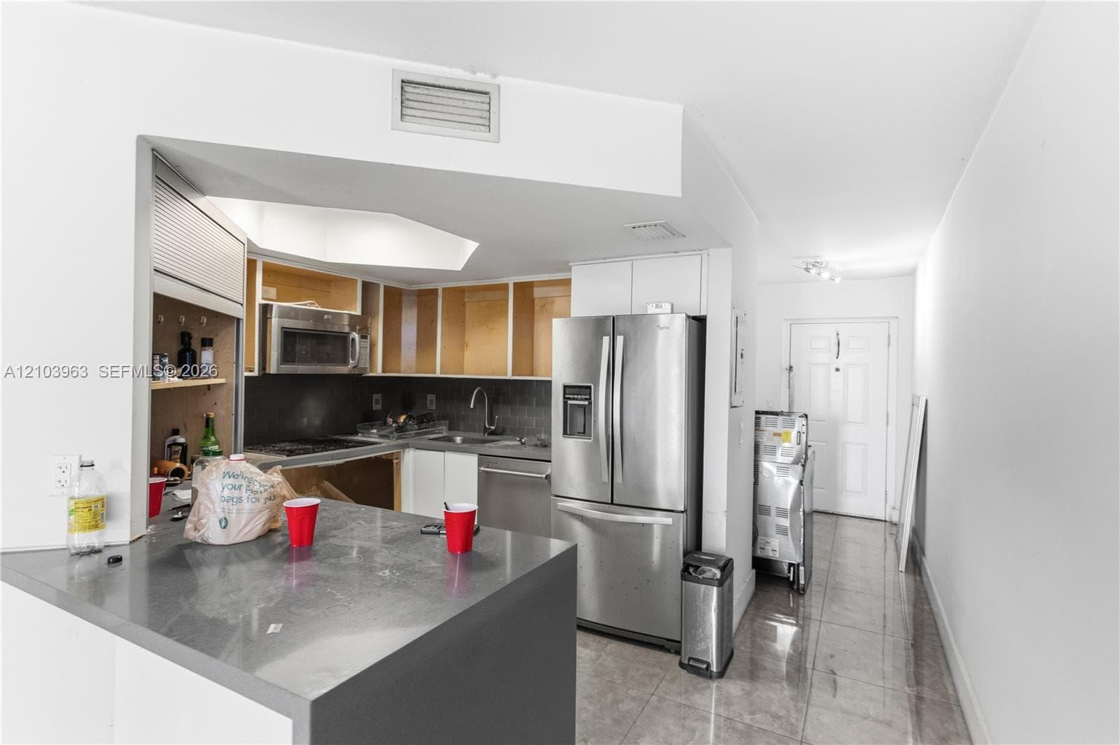 Kitchen featuring a solid-surface peninsula, stainless steel appliances, and tile flooring