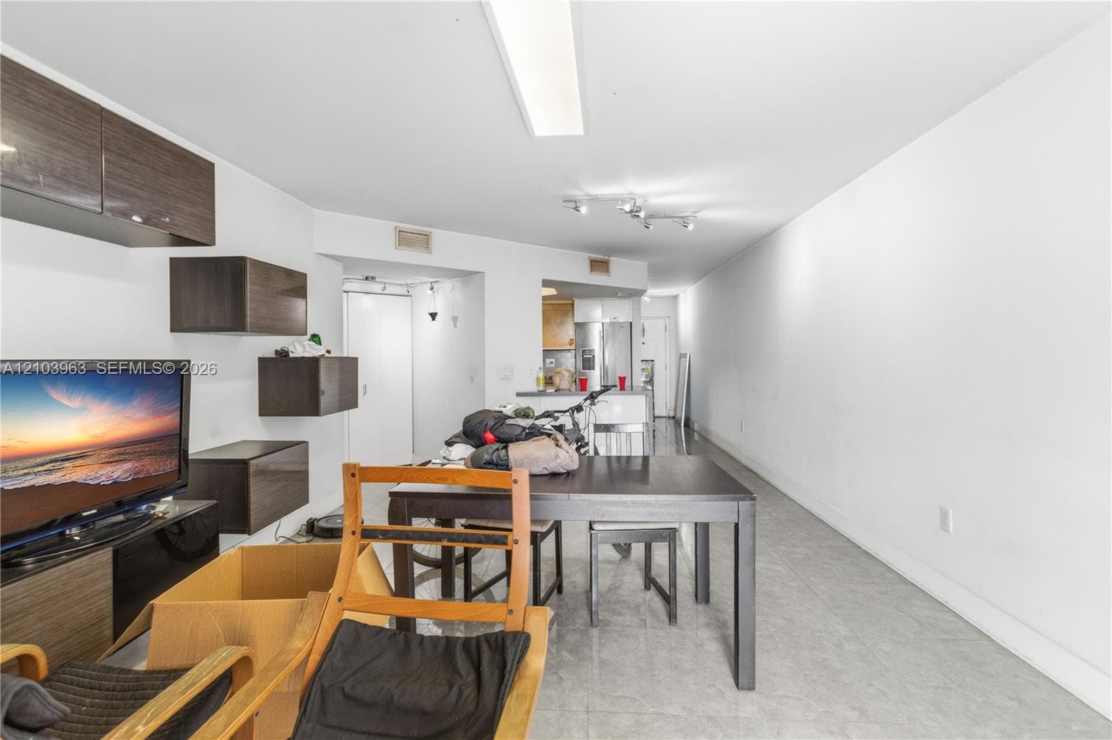 Open-concept interior featuring large-format tile flooring, wall-mounted dark wood-finish cabinetry, and recessed and track lighting