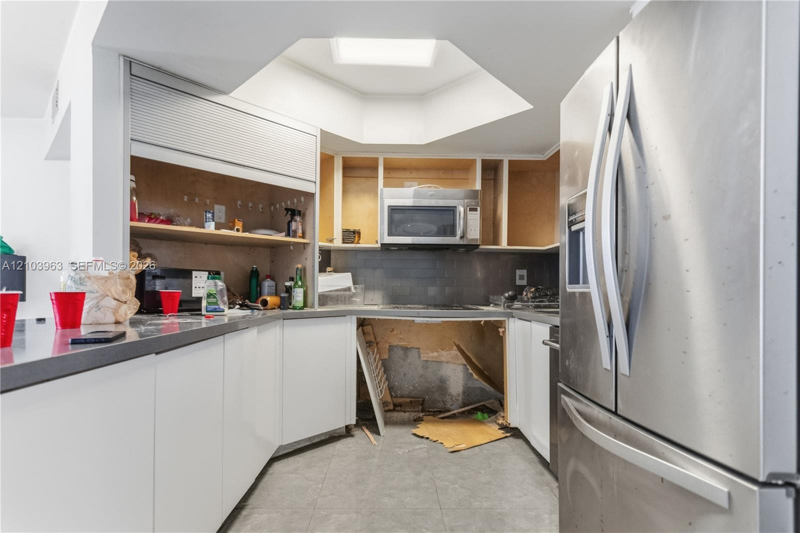 Kitchen featuring white cabinetry, stainless steel French-door refrigerator, built-in microwave, grey countertops, and a recessed ceiling feature with integrated lighting