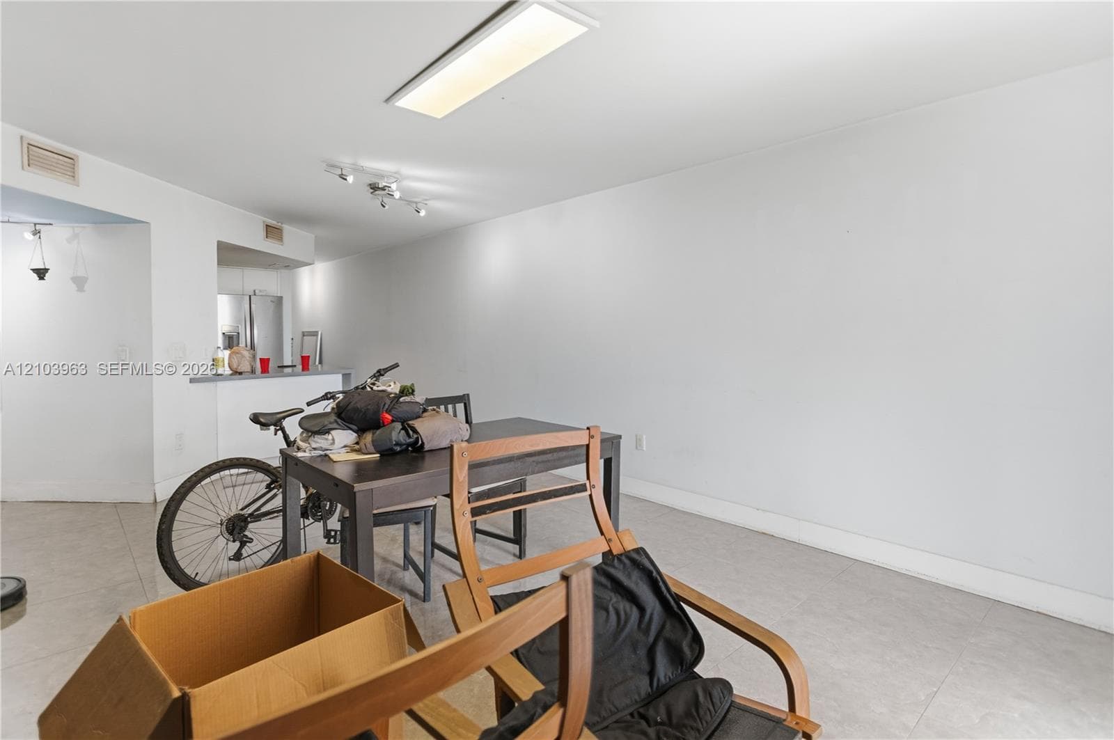 Open-concept area featuring light-toned tile flooring, recessed track lighting, and a flush-mount rectangular light fixture