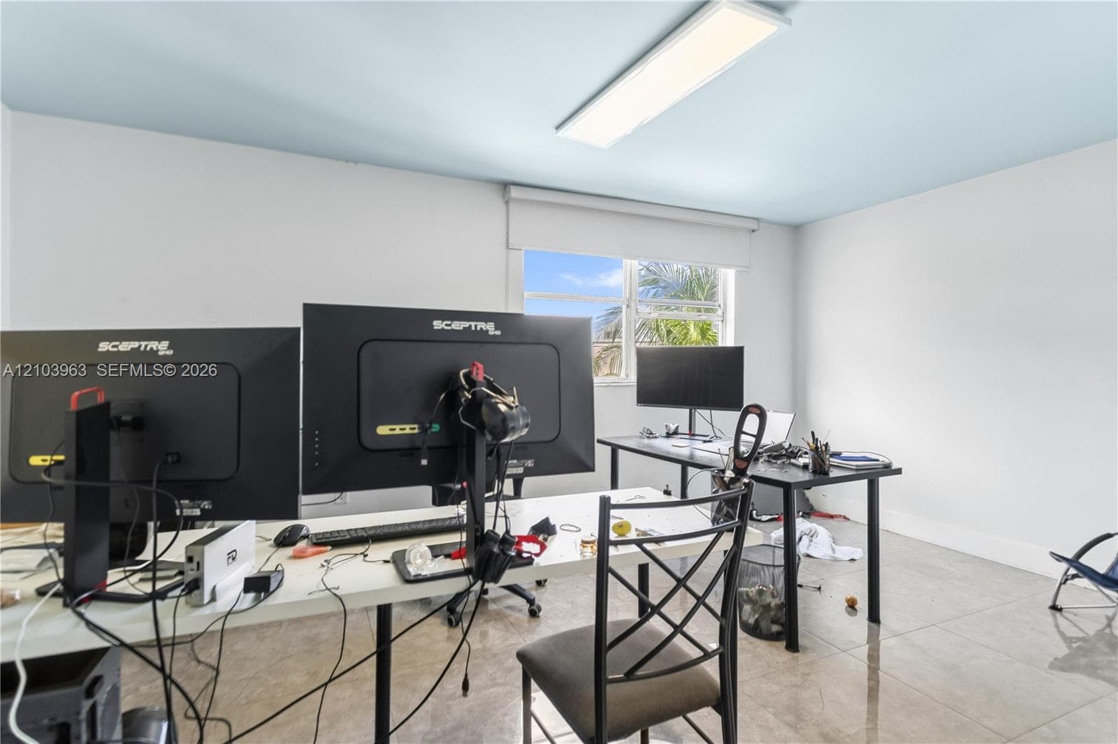Room with neutral-toned oversized tile flooring, recessed rectangular ceiling lighting, and a single-pane window with a roller shade