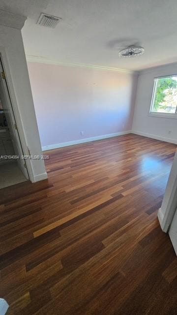 Room featuring wood-finish flooring, crown molding, a flush-mount crystal ceiling light fixture, and large-format window