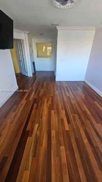 Wood-finish flooring featuring prominent grain patterns, crown molding, and a multi-pane glass door