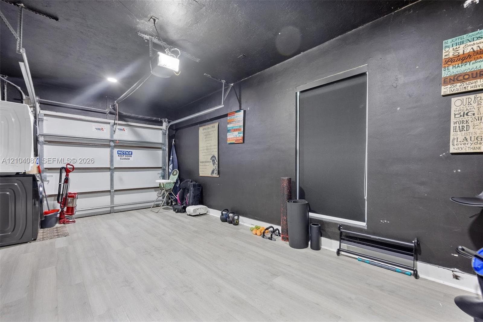 Light wood-finish flooring, overhead lighting, and a window with a blackout shade