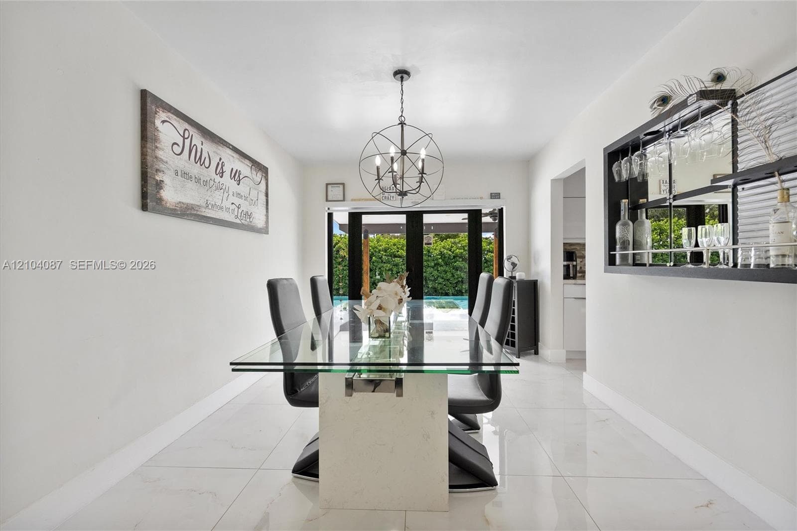 Recessed lighting, large format tile flooring, black multi-pane exterior doors, and a built-in wall bar with mirrored backing