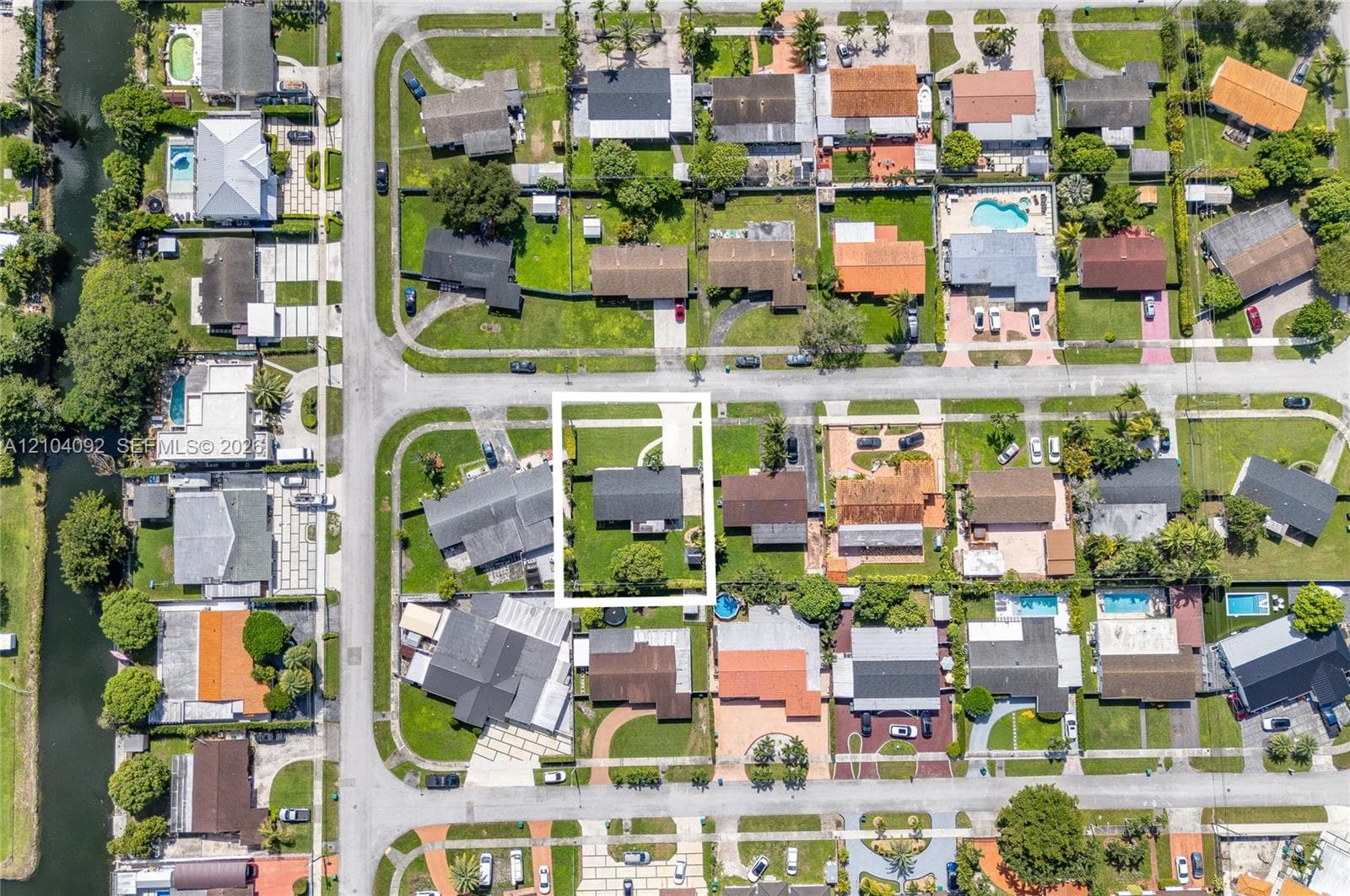 Aerial view of a residential lot featuring a paved driveway, a landscaped front lawn, and a fenced rear yard